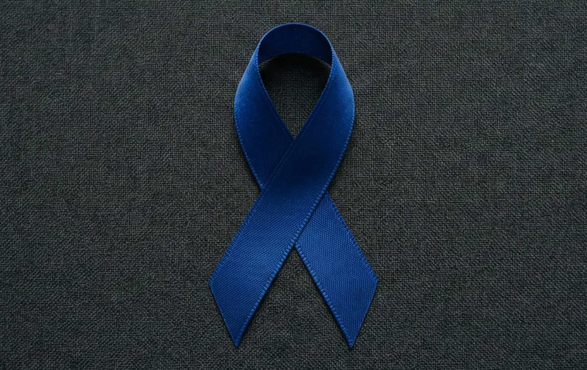 Blue colon cancer awareness ribbon on a dark textured background